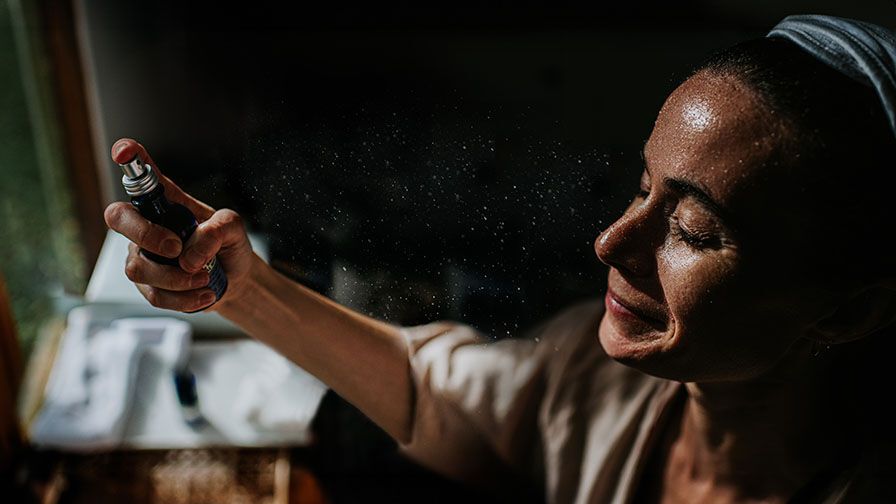 Mulher na menopausa a usar spray refrescante para aliviar afrontamentos 