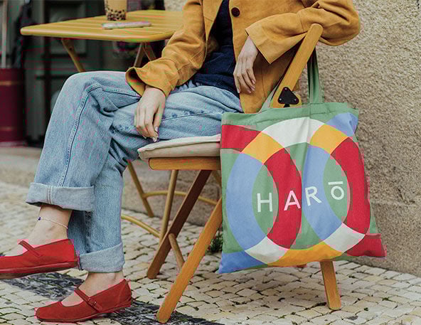 Rapariga sentada numa esplanada, com tote bag colorido em destaque