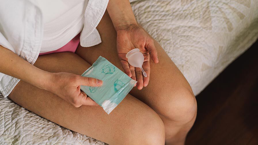 mulher a segurar alguns produtos menstruais