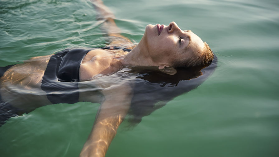 Mulher a flutuar na água, simbolizando equilíbrio e autocuidado durante a menopausa 