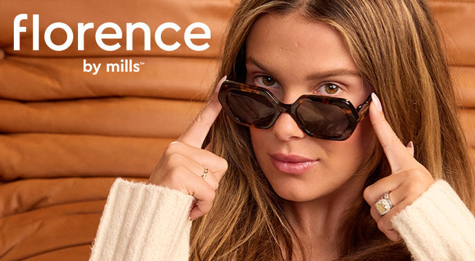Imagem promocional da florence by mills com modelo a segurar óculos de sol.
